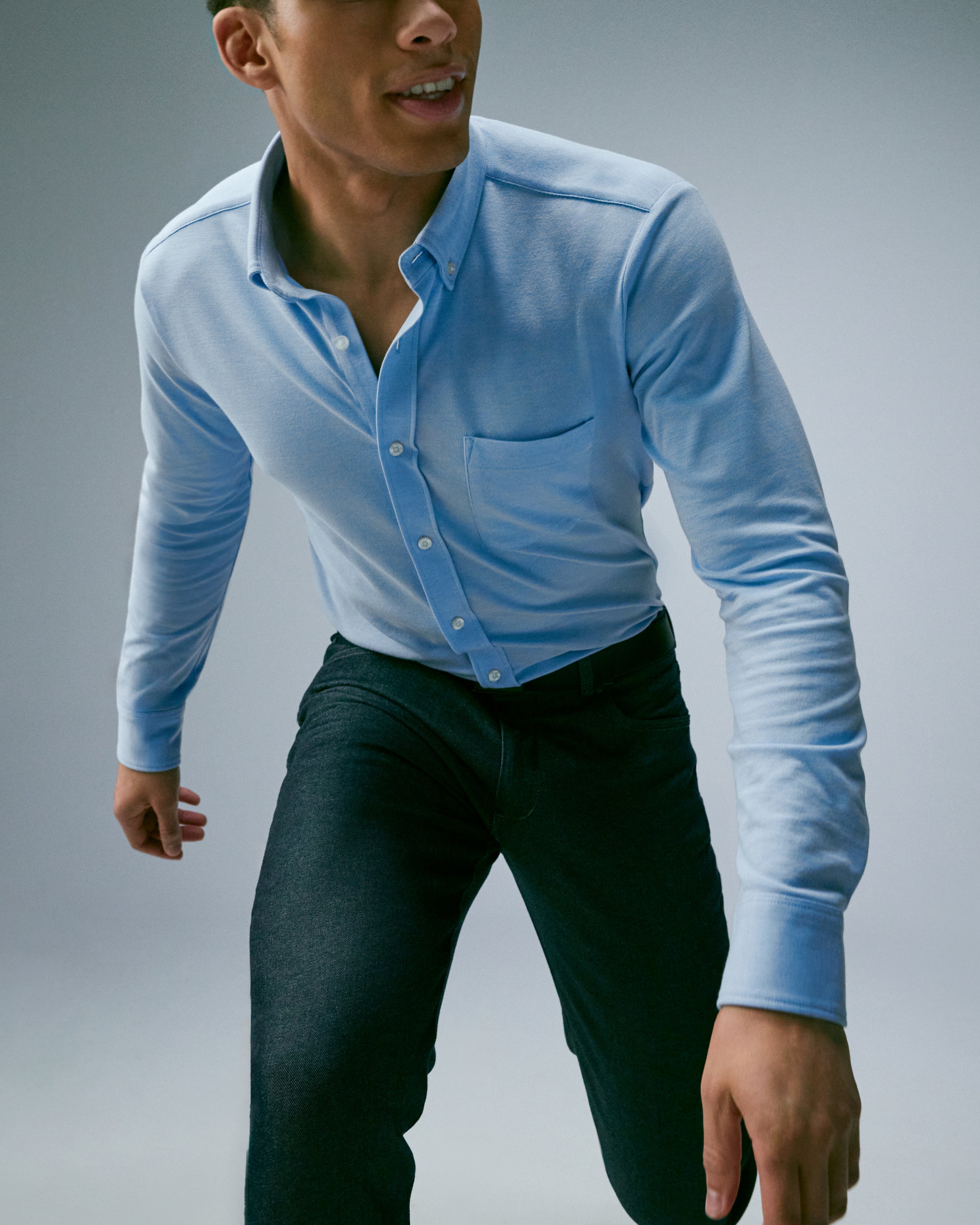 Man mid run towards the camera wearing baby blue SILVER button up and SILVER denim jeans