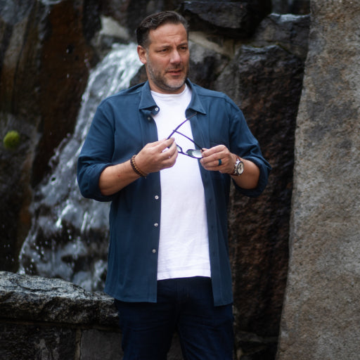 Main wearing a Pique Button Down shirt while outside and is holding sunglasses