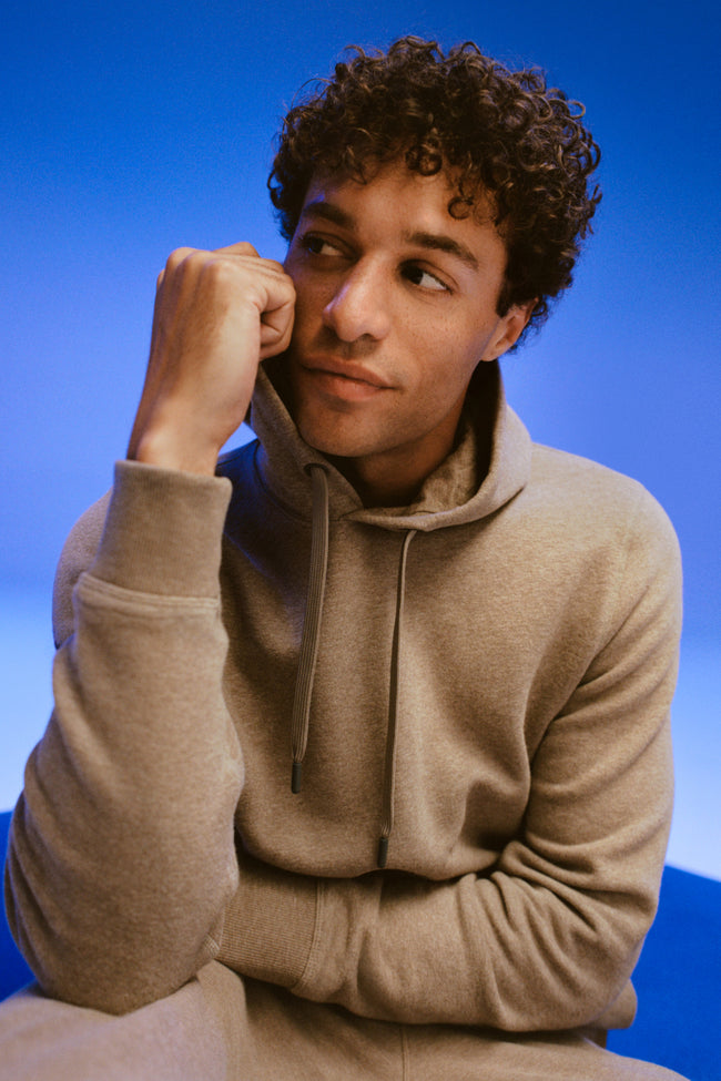 Man plays with the hoodie of his cream zip up hoodie